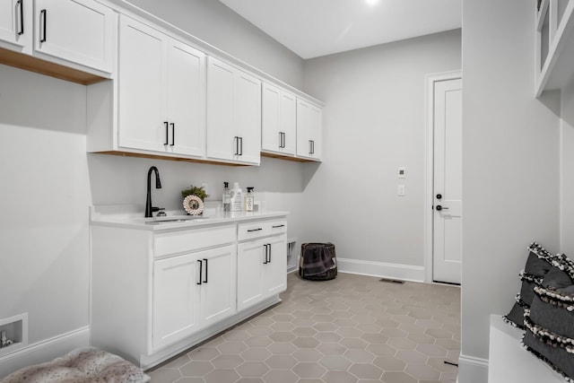 laundry area with a sink, light tile patterned flooring, visible vents, baseboards, and cabinet space