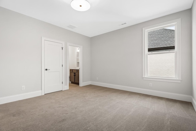 unfurnished bedroom with visible vents, ensuite bath, baseboards, and light colored carpet