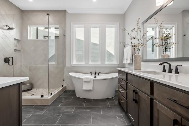 full bathroom featuring a freestanding tub, vanity, ornamental molding, and a stall shower