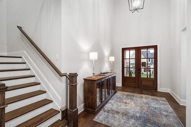 foyer with a towering ceiling, wood finished floors, french doors, baseboards, and stairs