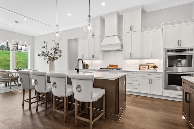kitchen featuring light countertops, appliances with stainless steel finishes, a sink, and custom range hood