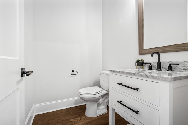 bathroom with baseboards, wood finished floors, toilet, and vanity