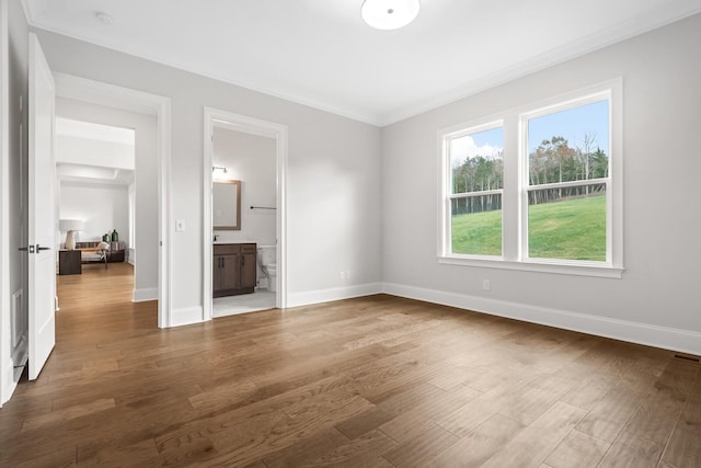 unfurnished living room featuring baseboards, ornamental molding, and wood finished floors