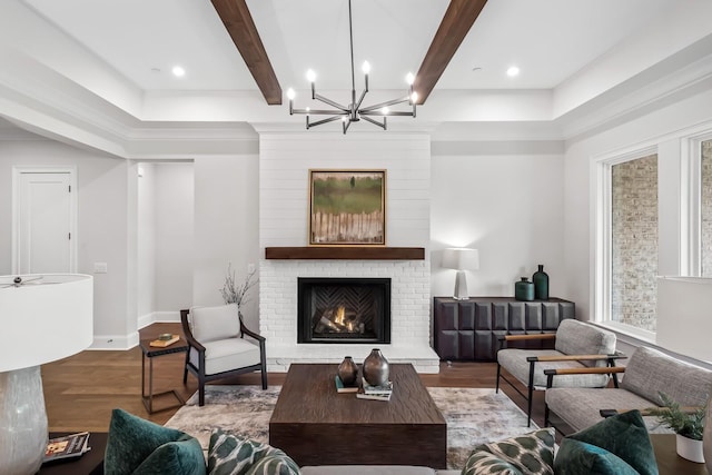 living area with wood finished floors, a chandelier, a wealth of natural light, a fireplace, and beam ceiling