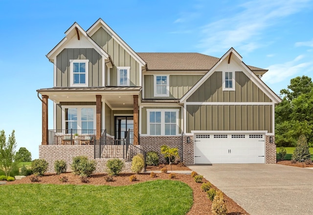 craftsman house with driveway, covered porch, an attached garage, board and batten siding, and a front yard