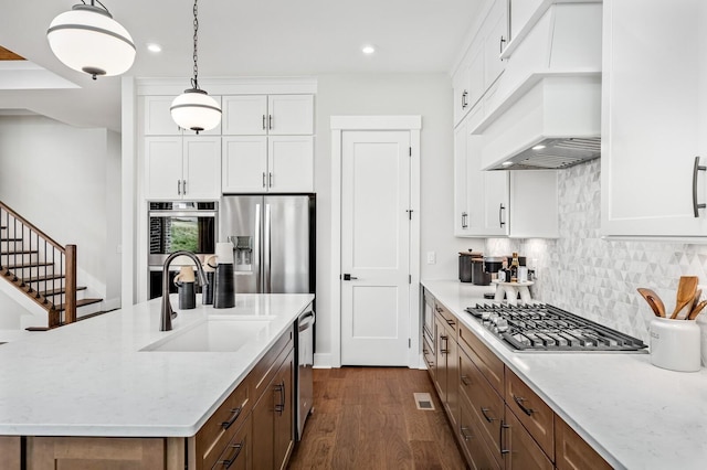kitchen with white cabinets, a sink, dark wood-style flooring, custom exhaust hood, and appliances with stainless steel finishes