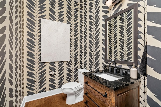 bathroom featuring toilet, vanity, wood finished floors, and wallpapered walls