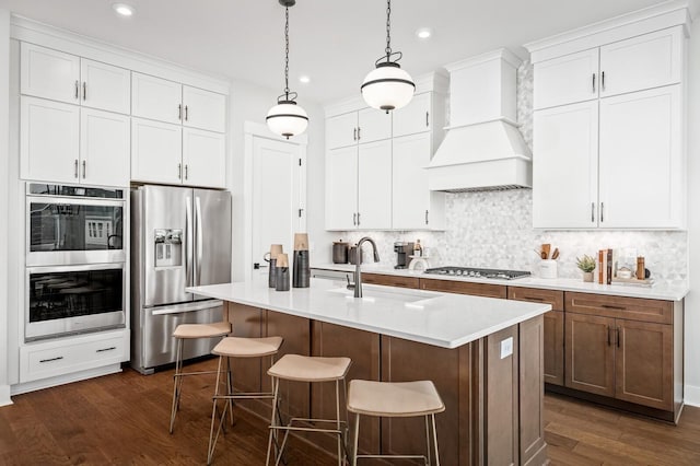 kitchen with a sink, stainless steel appliances, custom range hood, backsplash, and recessed lighting