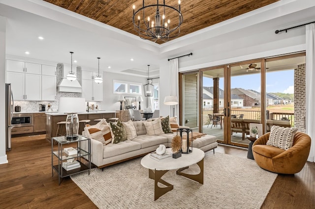 living room featuring a chandelier, a raised ceiling, dark wood-style flooring, and recessed lighting