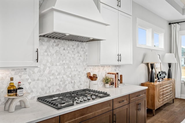 kitchen with white cabinets, stainless steel gas cooktop, tasteful backsplash, dark wood-style flooring, and custom range hood