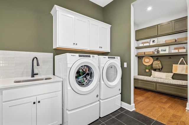 clothes washing area featuring cabinet space, washer and dryer, dark tile patterned flooring, and a sink
