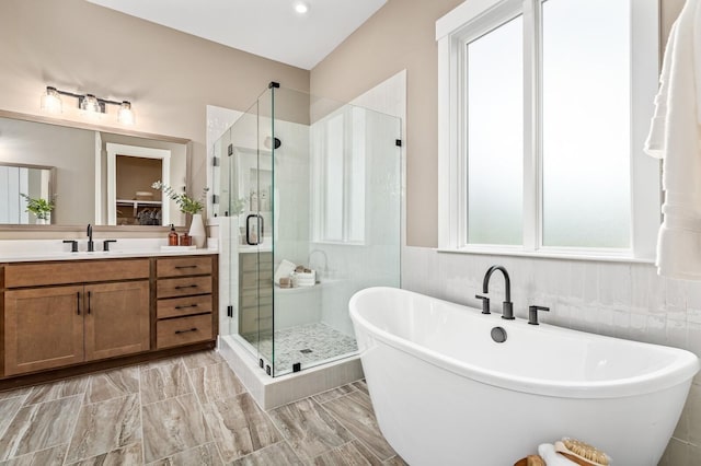 bathroom featuring a shower stall, a soaking tub, and vanity