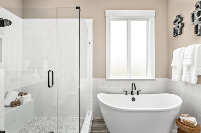 bathroom featuring tile walls, a wainscoted wall, a shower stall, and a freestanding bath