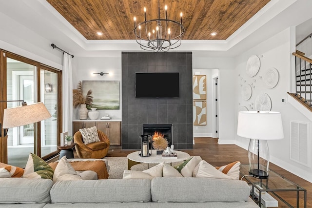 living room featuring stairway, wood ceiling, a tray ceiling, dark wood-style flooring, and visible vents