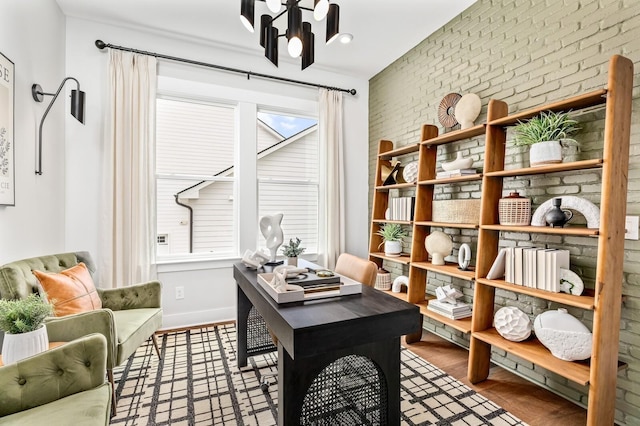 office space featuring brick wall, an inviting chandelier, and baseboards