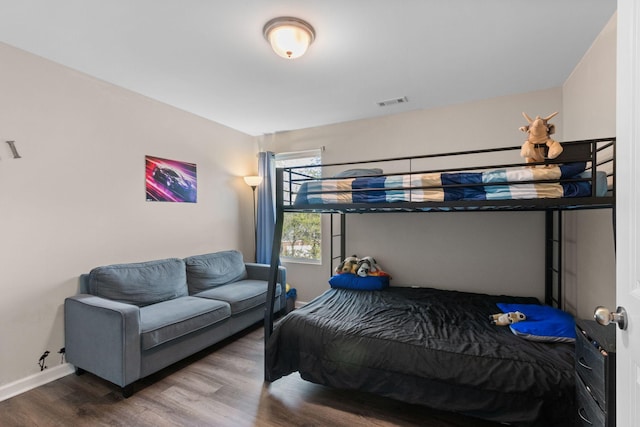 bedroom with baseboards, wood finished floors, and visible vents