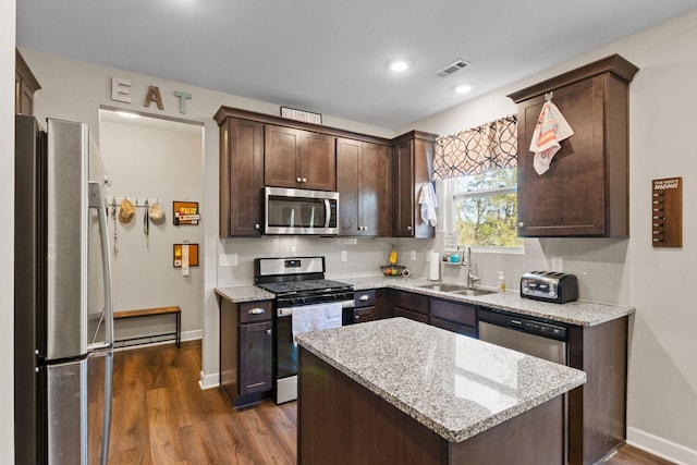 kitchen with dark brown cabinets, a sink, appliances with stainless steel finishes, dark wood-type flooring, and visible vents