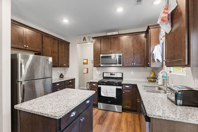 kitchen featuring dark brown cabinetry, a sink, backsplash, and appliances with stainless steel finishes