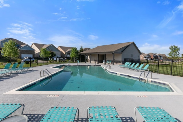 community pool with fence, a patio area, and a residential view