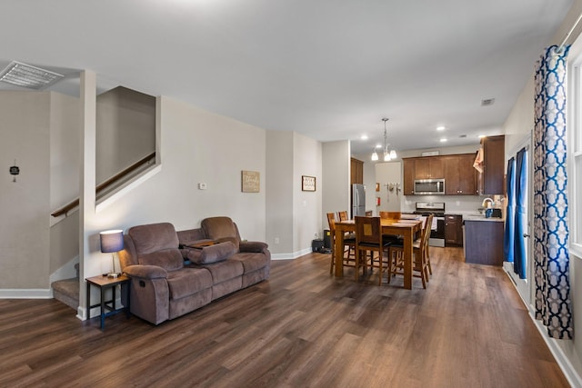 living area with a notable chandelier, visible vents, stairs, and dark wood-style floors