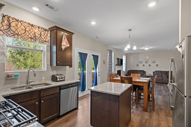 kitchen featuring stainless steel appliances, backsplash, visible vents, a sink, and open floor plan