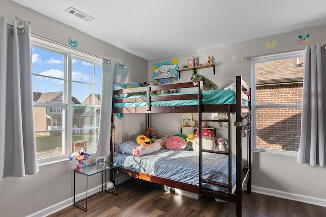 bedroom with baseboards, wood finished floors, and visible vents