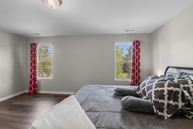 bedroom with wood finished floors, visible vents, and baseboards