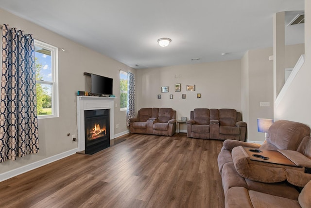 living area with stairway, wood finished floors, visible vents, baseboards, and a glass covered fireplace