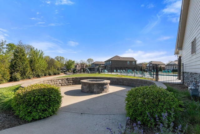 view of home's community with fence, a swimming pool, a fire pit, and a patio area
