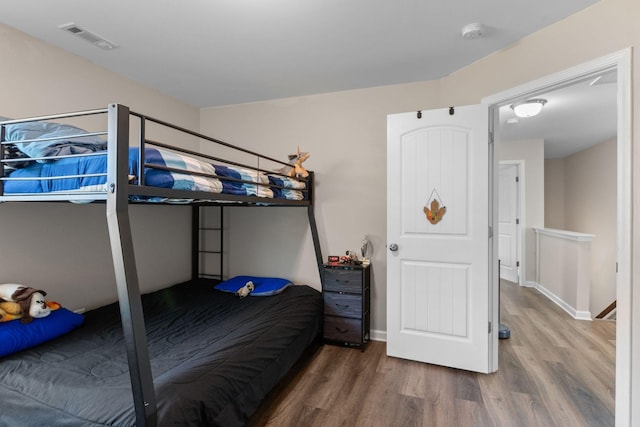 bedroom featuring baseboards, wood finished floors, and visible vents