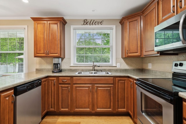 110 Ewingville Dr, Franklin, TN 37064 - kitchen with stainless steel appliances, a sink, brown cabinetry, ornamental molding, and healthy amount of natural light
