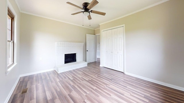 unfurnished living room with baseboards, wood finished floors, a fireplace, and ornamental molding