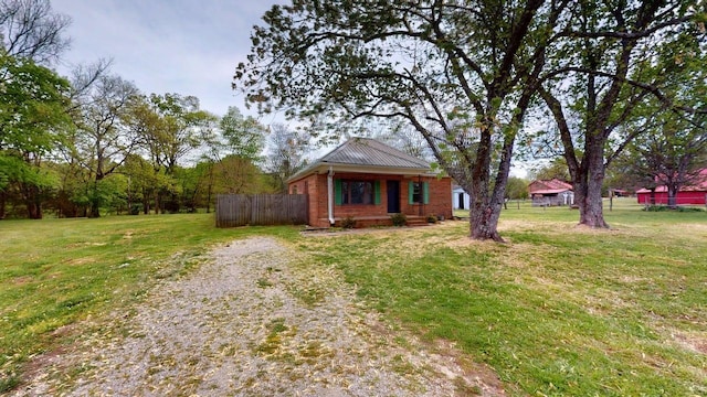 view of front of house with fence, a front lawn, brick siding, and metal roof