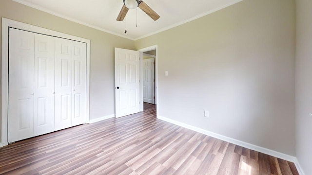 unfurnished bedroom with a ceiling fan, crown molding, a closet, light wood finished floors, and baseboards