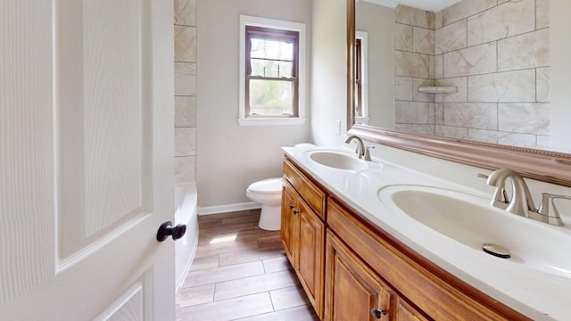 full bathroom with double vanity, toilet, walk in shower, and a sink
