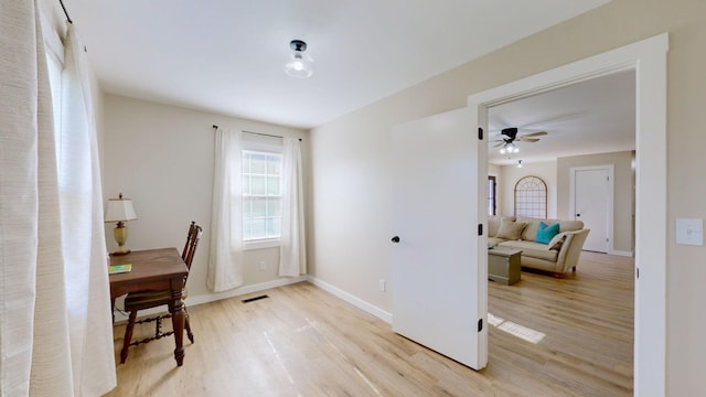 office area with light wood-type flooring, baseboards, visible vents, and ceiling fan