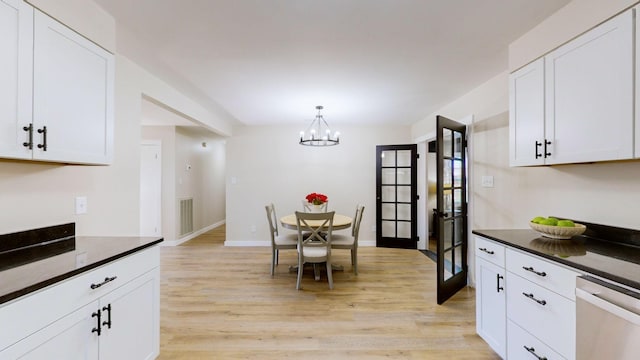 kitchen featuring dark countertops, dishwasher, an inviting chandelier, light wood finished floors, and white cabinets