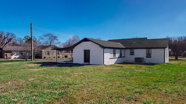 rear view of property with a yard, central air condition unit, and stucco siding