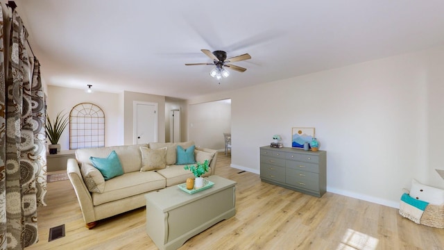 living area with light wood-style flooring, visible vents, baseboards, and ceiling fan
