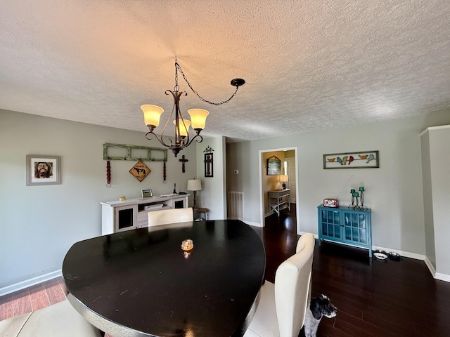 dining room featuring wood finished floors, a textured ceiling, baseboards, and a notable chandelier