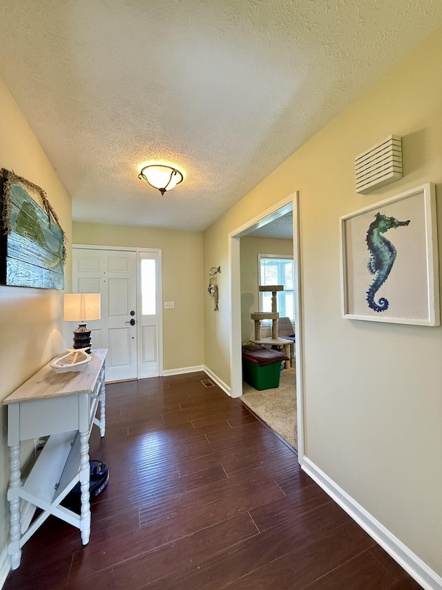 entrance foyer with dark wood-type flooring, plenty of natural light, and a textured ceiling