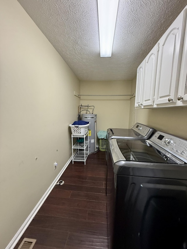 washroom featuring a textured ceiling, dark wood-style flooring, electric water heater, independent washer and dryer, and cabinet space