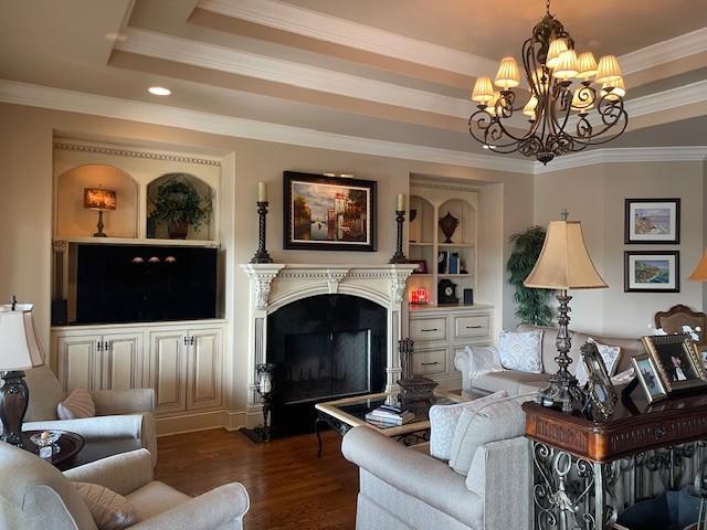 889 Plantation Blvd, Gallatin, TN 37066 - living area with a tray ceiling, dark wood finished floors, an inviting chandelier, a fireplace, and ornamental molding