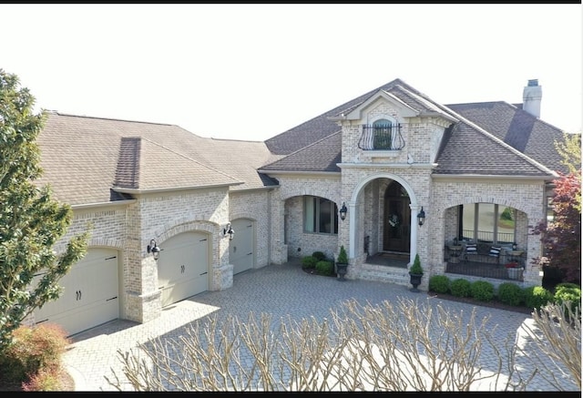 889 Plantation Blvd, Gallatin, TN 37066 - french country home featuring a chimney, covered porch, a garage, brick siding, and a shingled roof