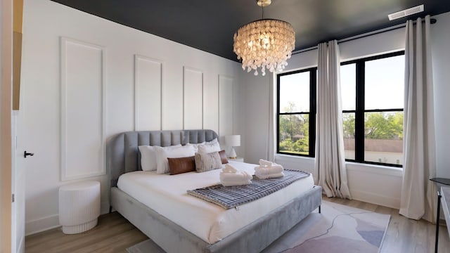 bedroom featuring baseboards, a notable chandelier, visible vents, and light wood-type flooring