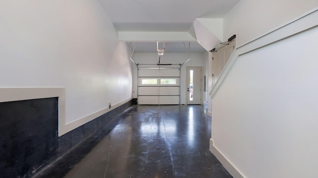 interior space featuring a towering ceiling, baseboards, and finished concrete floors
