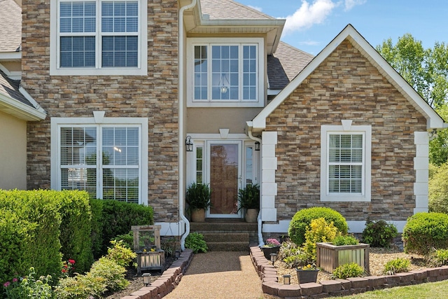 view of exterior entry featuring a shingled roof, stucco siding, and stone siding