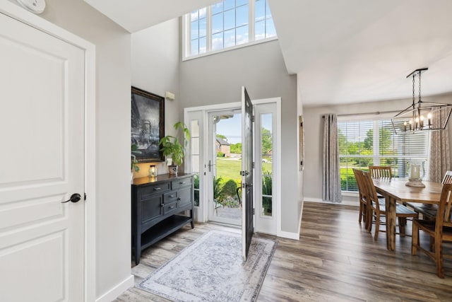 foyer entrance with an inviting chandelier, baseboards, and wood finished floors