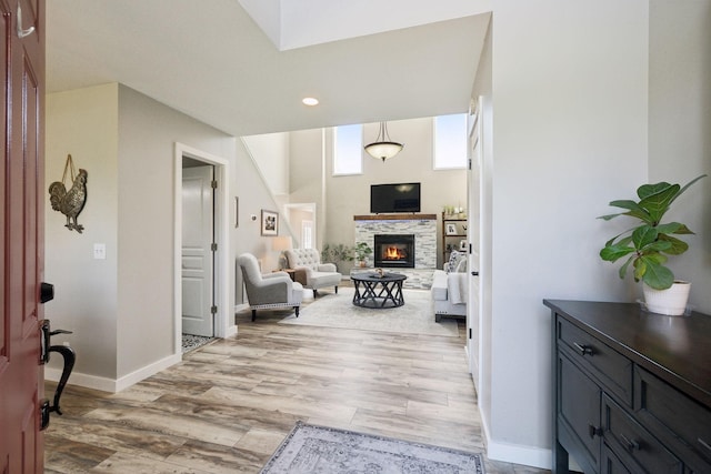 foyer featuring a stone fireplace, recessed lighting, light wood-style flooring, and baseboards