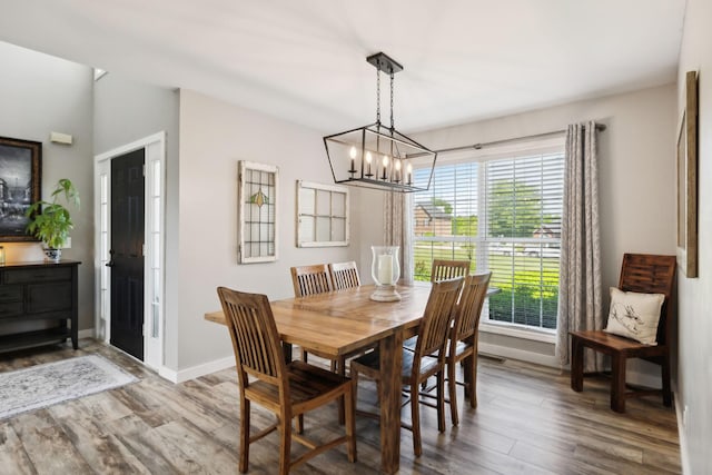 dining area featuring an inviting chandelier, baseboards, and wood finished floors